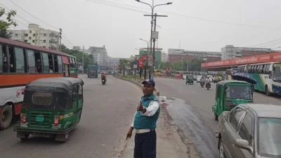 রাস্তায় দাঁড়িয়ে দায়িত্ব পালন করছেন ট্রাফিক পুলিশের এক সদস্য: দৈনিক খবর সংযোগ